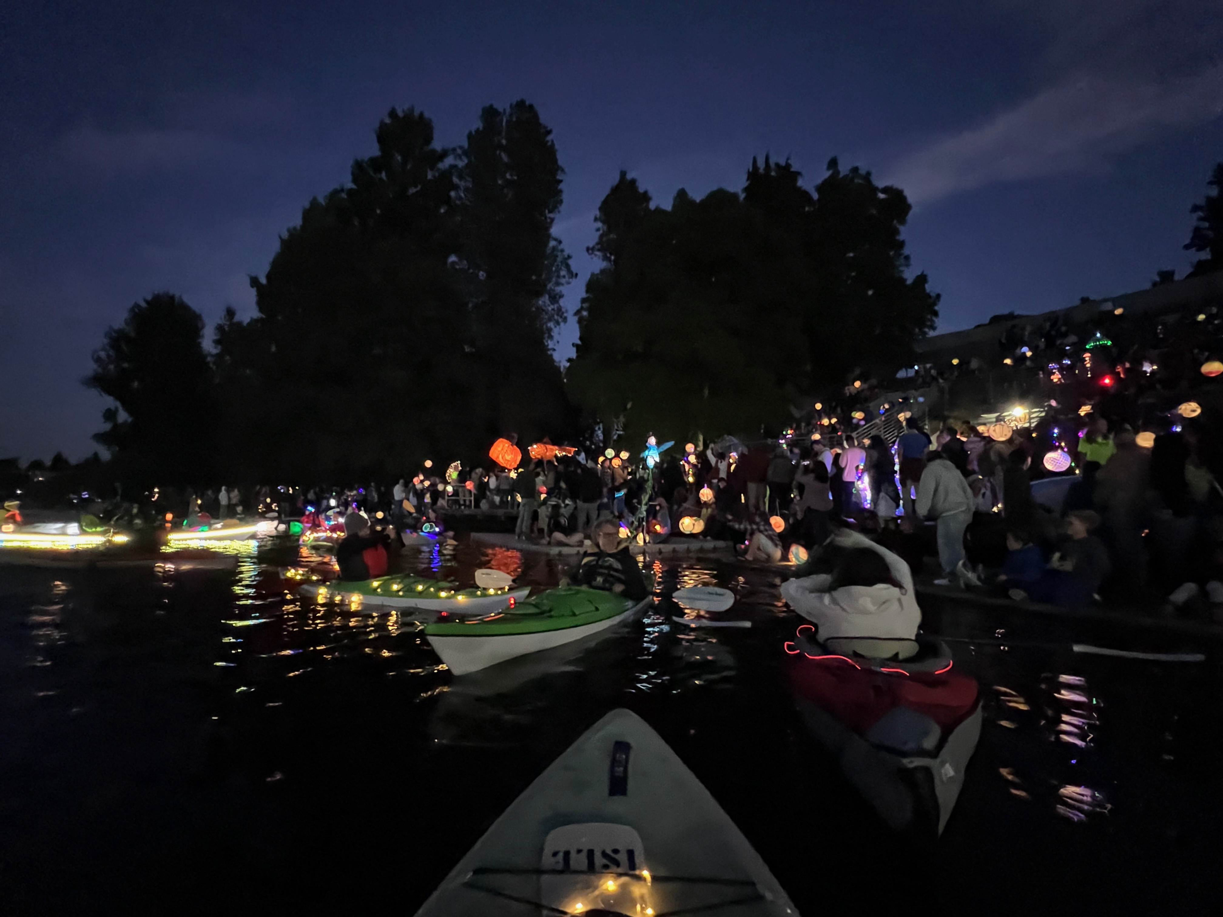 Kayakers on Green Lake at night surrounded by colorful lanterns at the Equinox festival