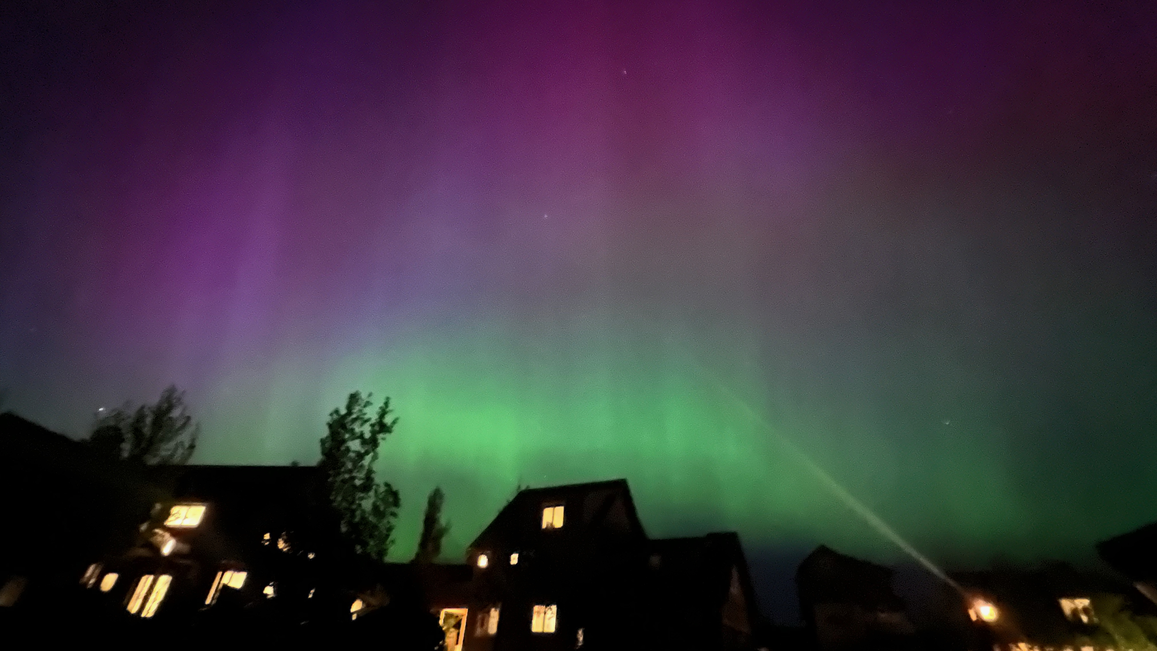 Northern lights in vivid green and purple over rooftops at Suncadia